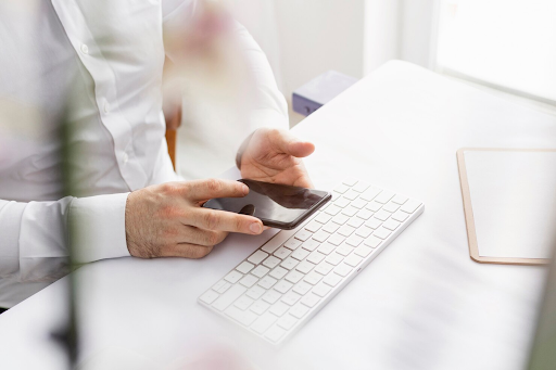 man-typing-on-phone-above-desk-keyboard